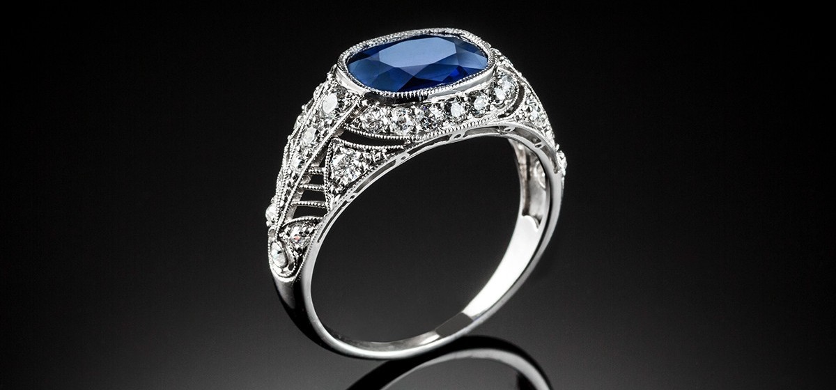 A PLATINUM ART DECO RING WITH A CUSHION SHAPE SAPPHIRE AND TRANSITION CUT DIAMONDS