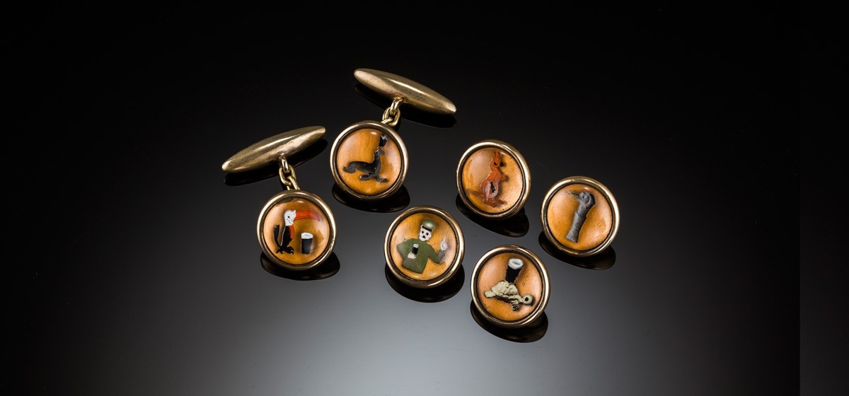 A 1920s set of reverse intaglio Essex crystal style Guinness cuff links and buttons / studs depicting the zoo keeper and his animals
