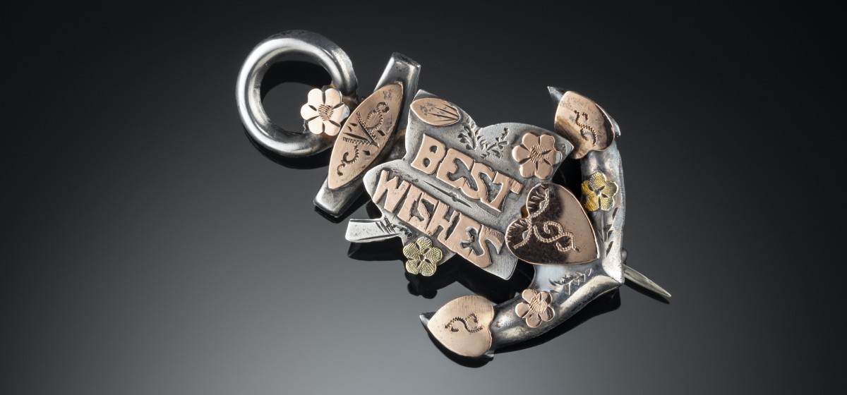 VICTORIAN SWEETHEART BROOCH/ PENDANT PROFUSELY DECORATED WITH GOLD HEARTS, FORGET ME NOTS AND “BEST WISHES” ON A SILVER ANCHOR