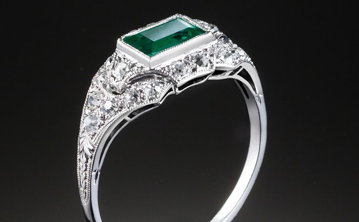 An Art Deco step cut emerald and diamond ring