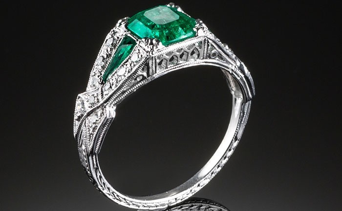 An Art Deco diamond and emerald ring with emerald shoulders