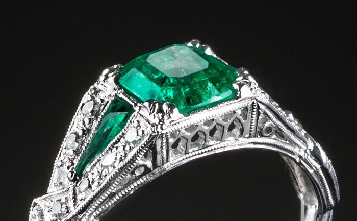 An Art Deco diamond and emerald ring with emerald shoulders