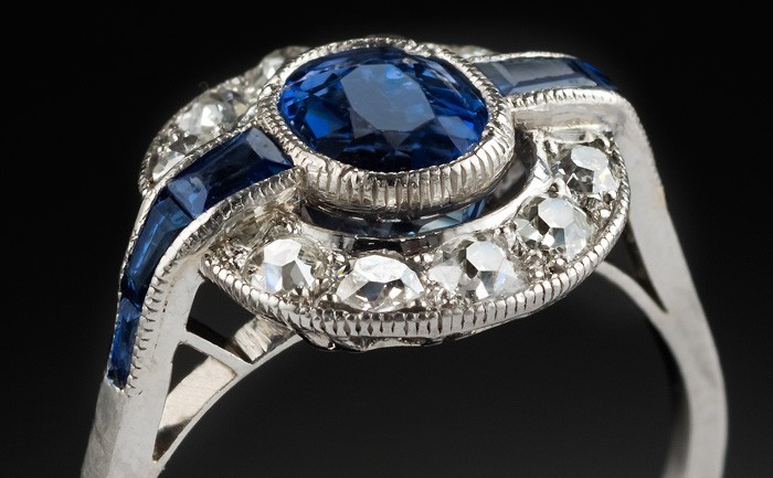 Detail of an Art Deco platinum, sapphire and diamond cluster ring with faceted sapphire shoulders