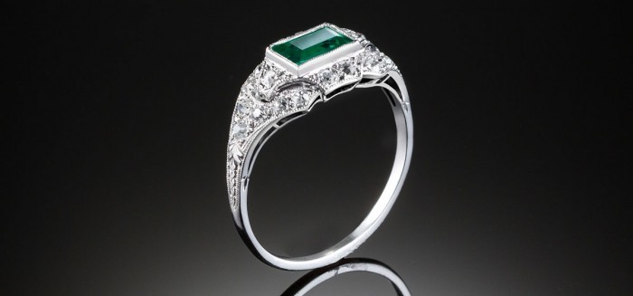 An Art Deco step cut emerald and diamond ring